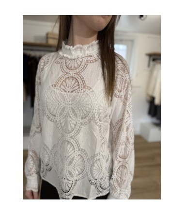 Femme portant une blouse blanche en dentelle colmatant à volants et motifs circulaires détaillés