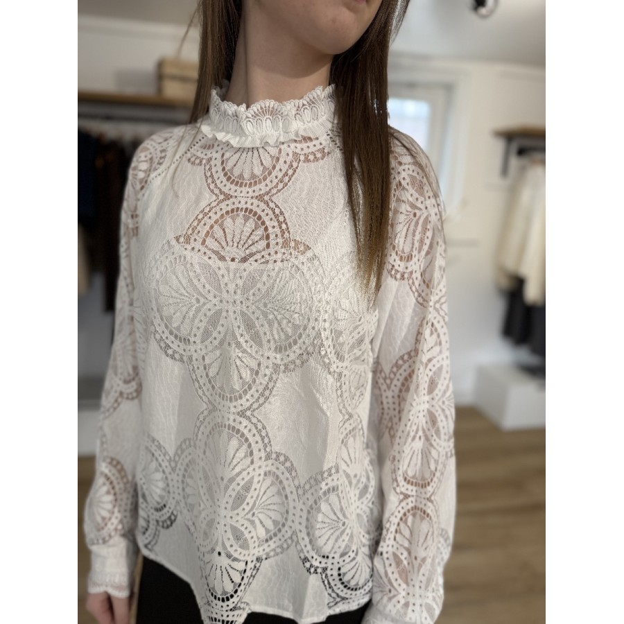Femme portant une blouse blanche en dentelle colmatant à volants et motifs circulaires détaillés